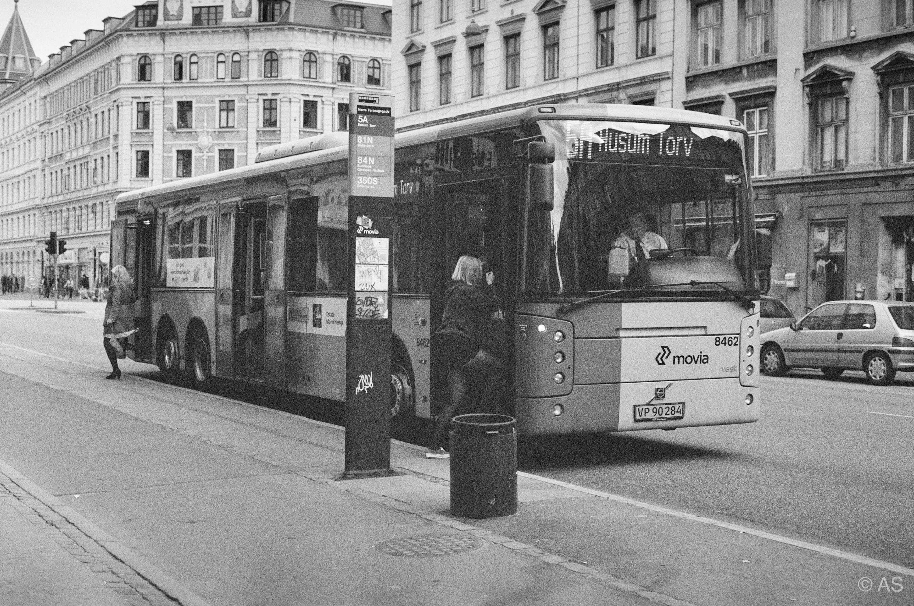 Copenhagen bus at a stop with passengers boarding on a quiet city street