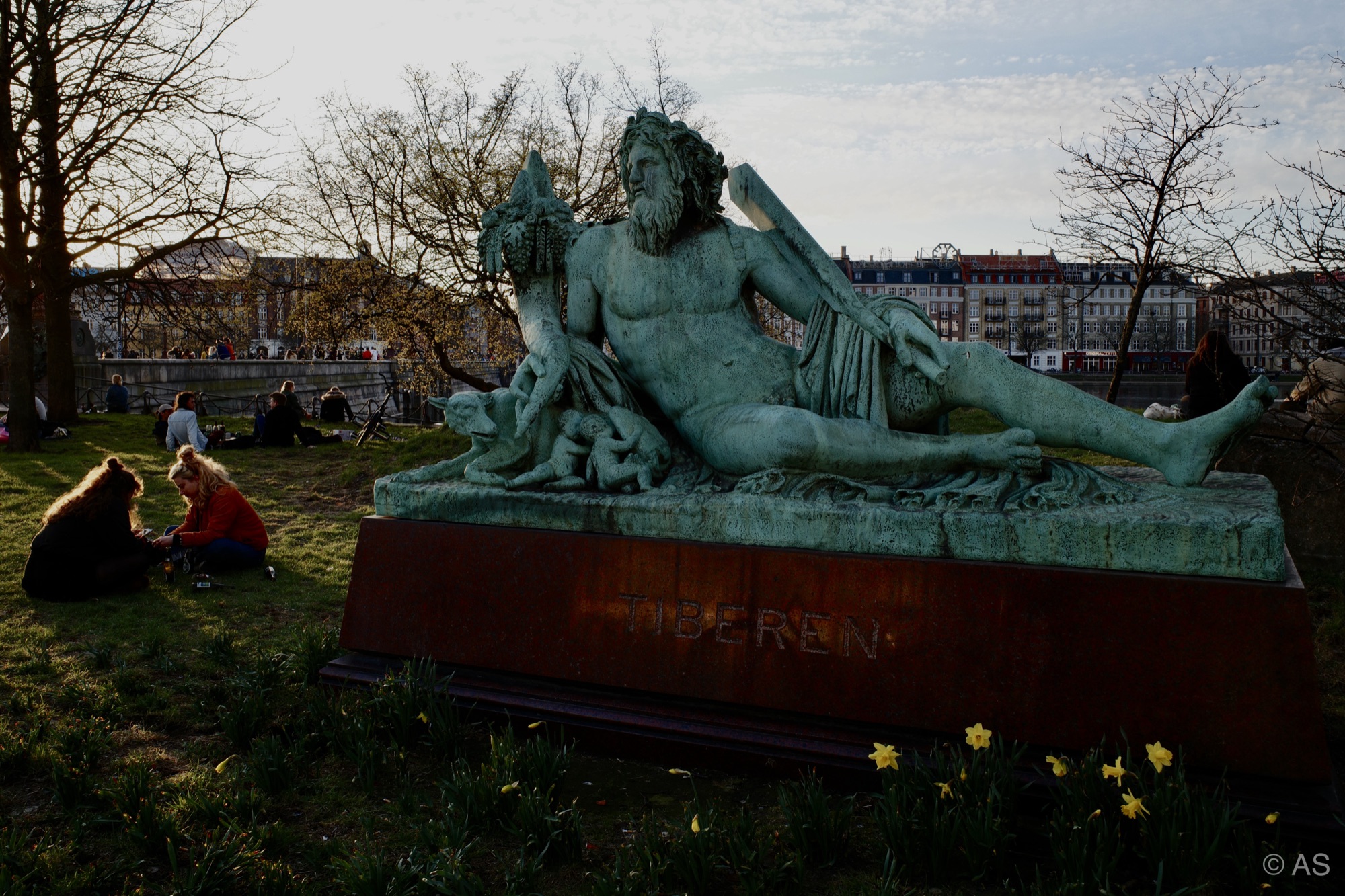 Green bronze statue of Tiberen in a Copenhagen park with daffodils
