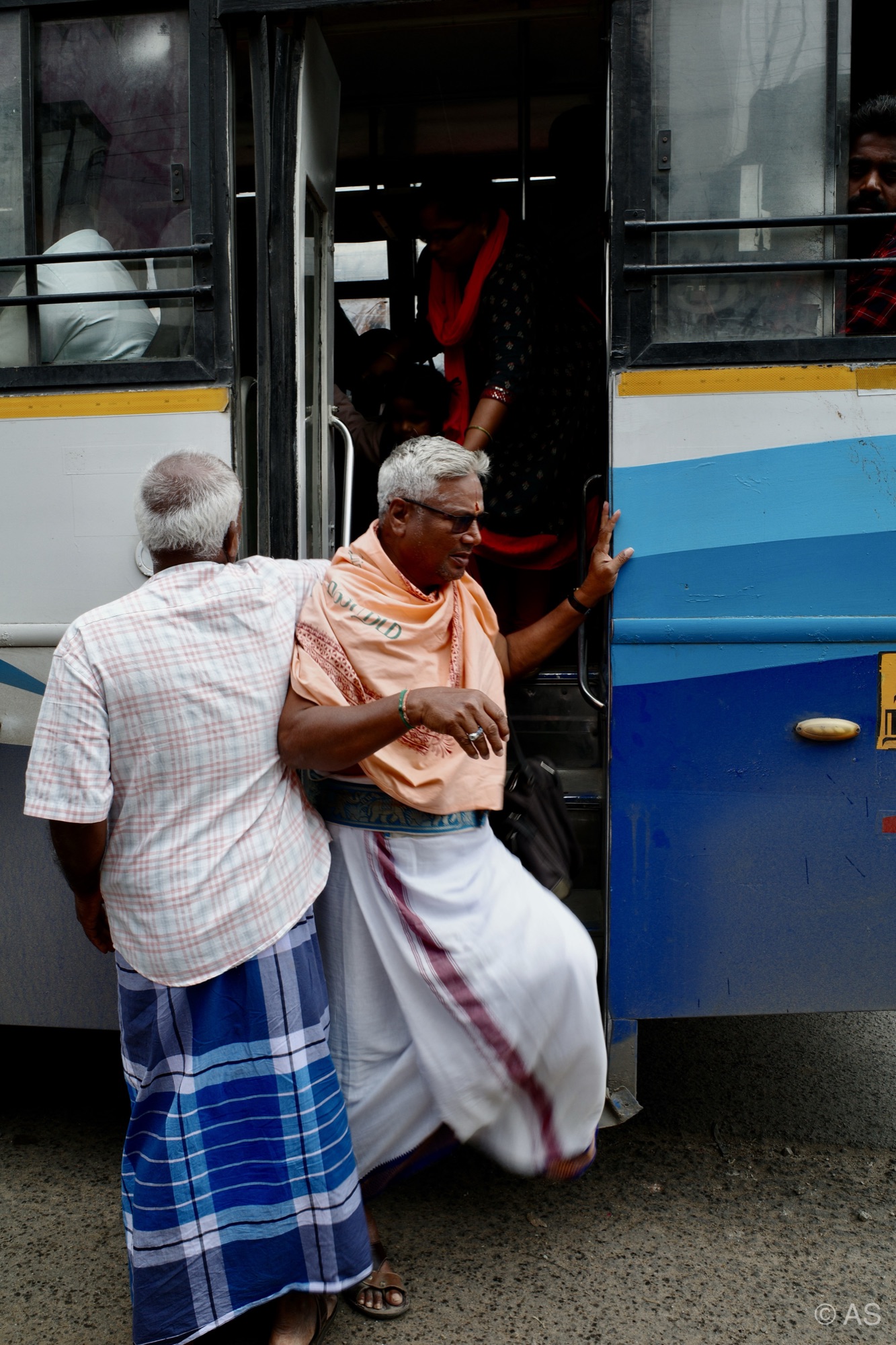 Men boarding a blue bus at a stop in India