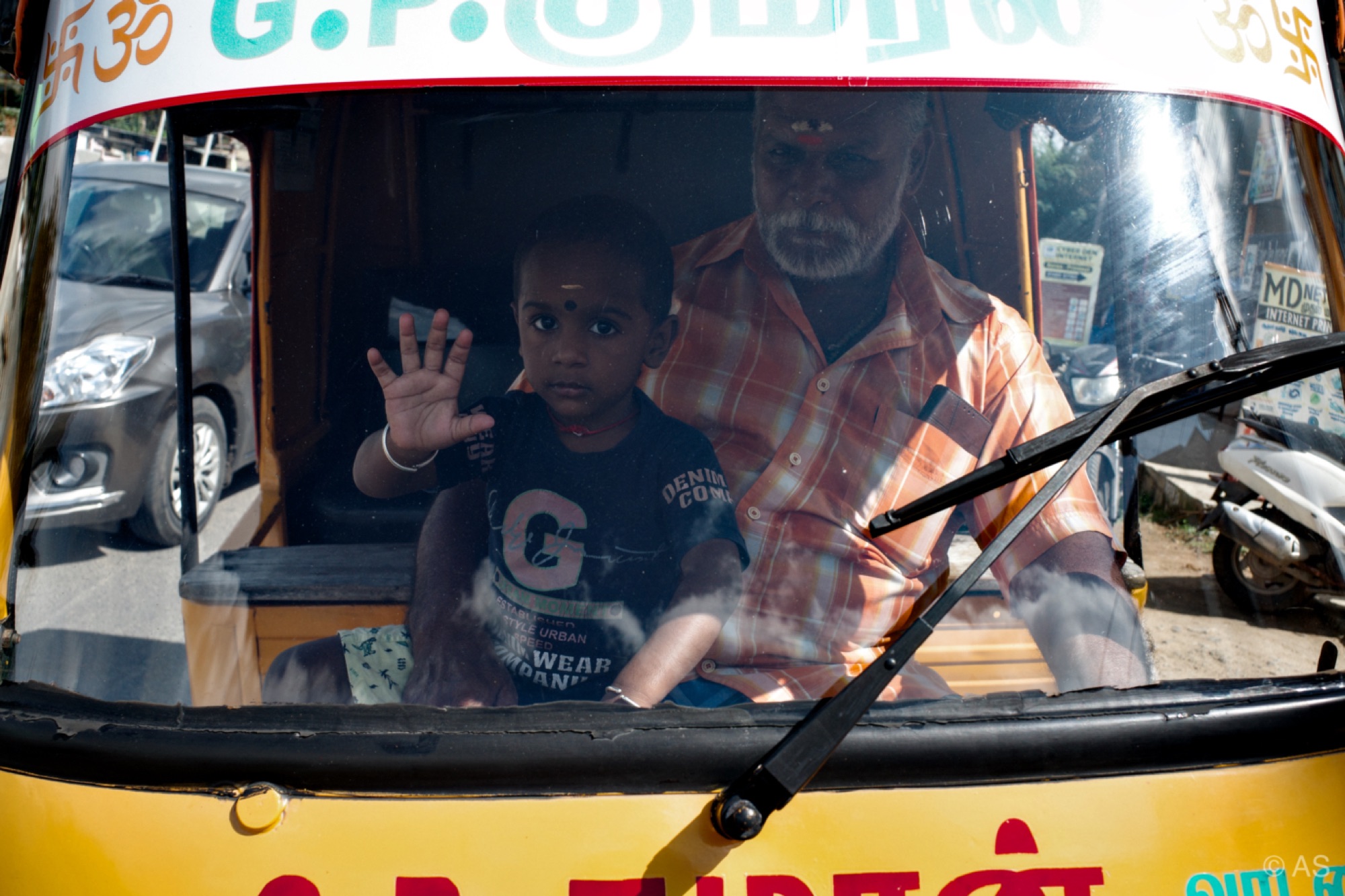 Child waving from the front of an auto-rickshaw